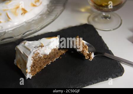 Closeup of a serving of pecan pie served on a black slate next to a glass of alcoholic drink Stock Photo
