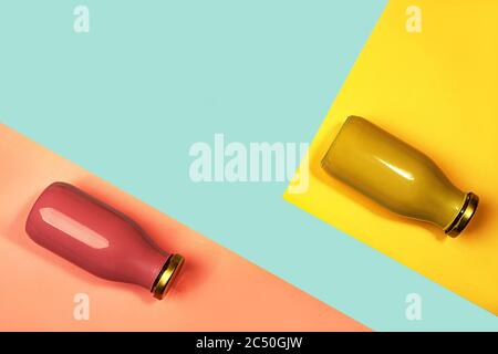 Bottles of multicolored juices or smoothies on yellow, pink coral and trendy mint green blue background. Flat lay, top view, close up. Minimal style. Stock Photo