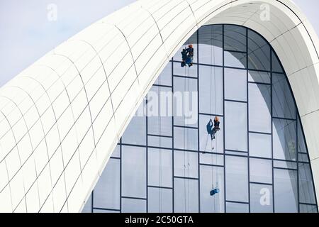 Window cleaners at work. Window cleaner, in the suspension system. Industrial mountaineering. Stock Photo