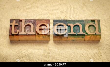 The end concept - words in vintage wooden letterpress printing blocks stained by color inks against handmade textured paper Stock Photo
