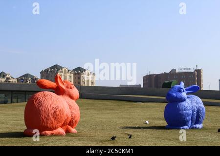Two large sculptural hares red and blue on the green grass  Stock Photo