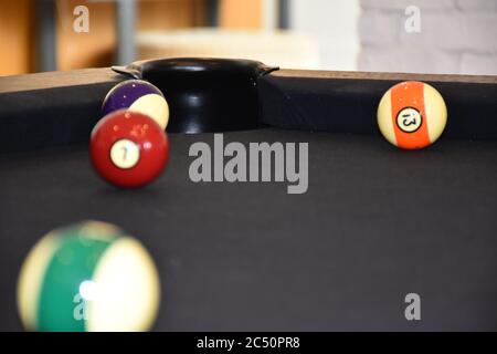 The pocket or hole of a billiard table that is covered with black billiard cloth balls are out of focus. The pocket is protected with plastic and in t Stock Photo