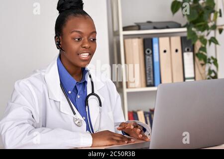African female doctor talk to patient by online webcam video call on laptop. Stock Photo