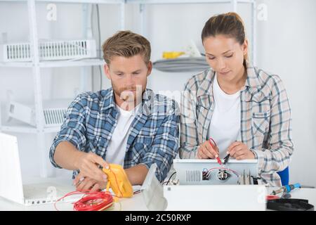 male and female technicians using multimeter to test electrical appliance Stock Photo