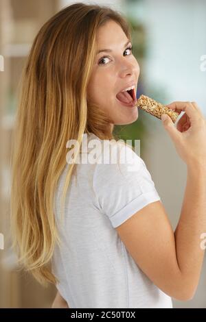 beautiful young woman eating cereal candy bar Stock Photo