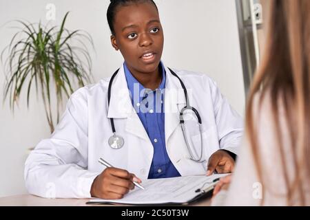 Afro american female doctor physician gp speaking consulting sick woman patient. Stock Photo