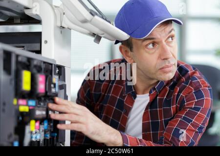 technician using a tablet to fix a printer Stock Photo