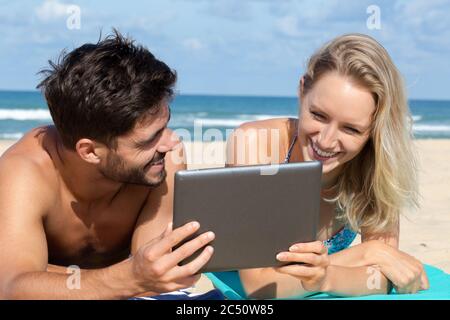 couple using tablet on the beach Stock Photo