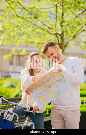 Man and a woman with bicycle carefully examining map Stock Photo