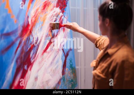 Woman relaxing in art studio painting on large canvas. Modern artwork paint on canvas, creative, contemporary and successful fine art artist drawing masterpiece Stock Photo