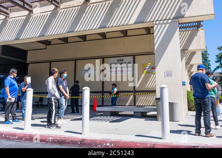 June 16, 2020 Santa Clara / CA / USA - People waiting in line to enter a recently reopened DMV office; they are wearing masks and are social distancin Stock Photo