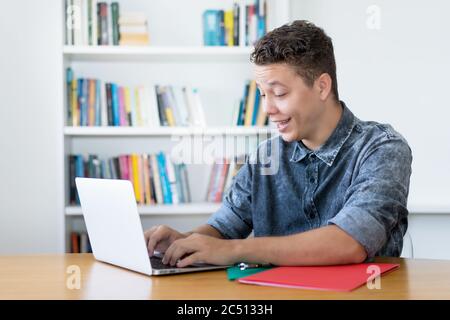 Young german computer science student working at computer indoors at desk at home Stock Photo