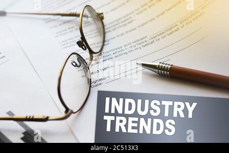 Iindustry trends text on a card. Agreement with pen and glasses. Selective focus. Business work office career concept Stock Photo