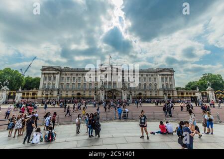 Buckingham Palace with unknown tourists sightseeing and a dramatic cloudscape in the sky above. Stock Photo