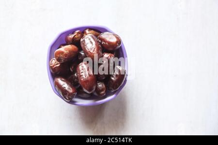 dates on purple bowl white wood background Stock Photo