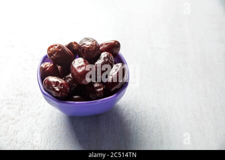 dates on purple bowl white wood background Stock Photo