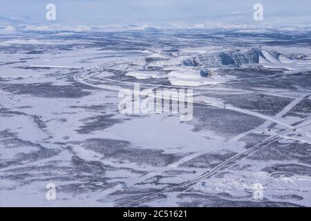 Aerial shot of the Kiruna area with a road in Lapland in Sweden in winter. At the top right the factories of the LKAB, a large Swedish mining company Stock Photo