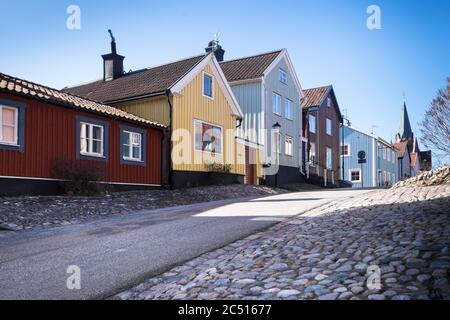 Street with typical Swedish colored houses with the Sankt Petri Kyrka or Saint Peter Church on the right in Västervik (Vastervik) in Sweden Stock Photo