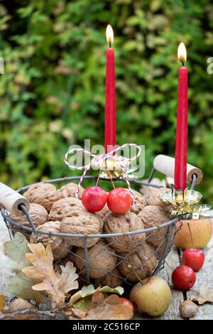 walnuts in basket and red candles as autumn decoration Stock Photo