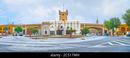 Panorama of Earthen Gate (Puertas de Tierra) with tall tower, arched passes and flower beds, Cadiz, Spain Stock Photo