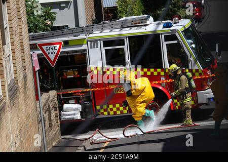 The NSW Fire Brigades workers in yellow hazardous materials protective clothing are washed clean at the Woolley Street end of St James Lane in Glebe. Stock Photo