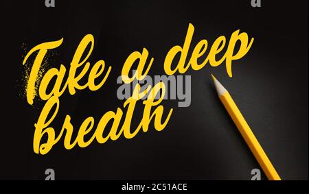 Take a Deep Breathe words in yellow lettering on black and pencil besides. Tranquility humility psychological concept Stock Photo