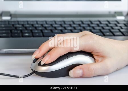 Female hand using computer mouse in front of laptop Stock Photo