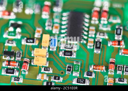 Green printed circuit board. Surface mount technology of electronic components. Abstract close-up of small diodes, capacitors or transistors. E-waste. Stock Photo