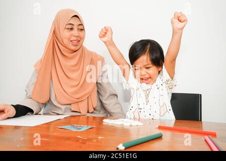 Young musilm woman with her cute daughter playing and learning at home. Motherhood having good time. Stock Photo