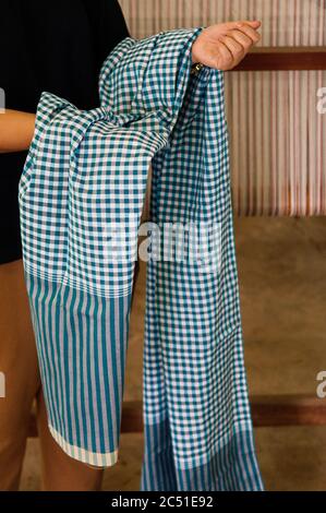 Asain woman holding Pha Khao Ma, Thai traditional multi-purpose loincloth with scottish pattern colourful fabric. Stock Photo