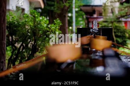Selective focus on water bubbling up from a fountain at one end of a "temizuya", where water is held for cleansing rituals at Japanese shrines Stock Photo