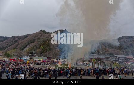 A large crowd watches as smoke begins to billow from the pile of green kindling at the annual fire-walking festival near Mount Takao, west of Tokyo Stock Photo