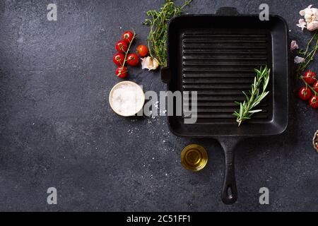 Flat lay top view black cast iron skillet for barbecue. Frying pan with cooking ingredients and spices on concrete background with copy space Stock Photo