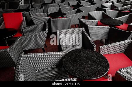 Numerous empty sets of dark gray and red chairs and tables crowded closely together Stock Photo