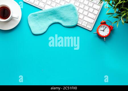 Hard exhausing work concept. Sleep mask on blue office desk top view copy space Stock Photo
