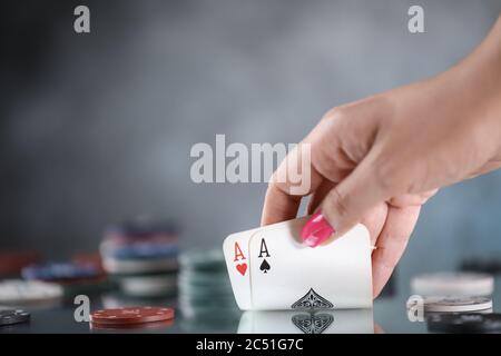Close up of a woman hand holding poker playing cards, with cards of four aces on the background. Online gambling. Addiction. Stock Photo