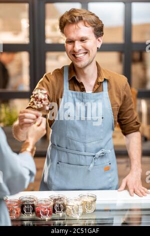 Portrait of a cheerful salesman in uniform selling ice cream at the shop Stock Photo