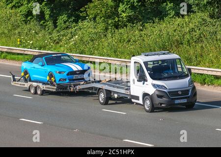 2017 blue white Ford Mustang GT V8 towed by new 2020 white Fiat Ducato 2.3 130bhp Recovery Truck Car Transporter Euro 6;  Vehicular traffic on tow, moving vehicles, cars driving vehicle towing car trailer on UK roads, motors, motoring on the M6 motorway Stock Photo