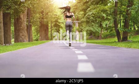Morning Jogging. Unrecognizable Girl Running In Empty Park, Rear View Stock Photo