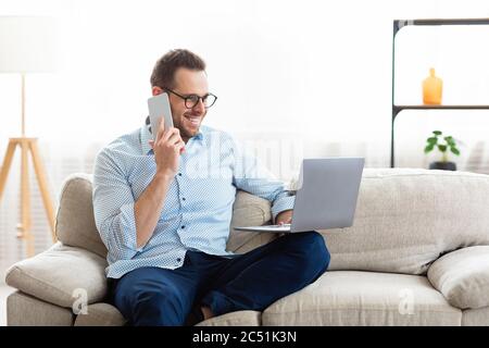 Portrait of successful smiling worker using cell phone and pc Stock Photo
