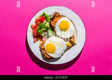 Fried eggs from two eggs on a pink background Stock Photo