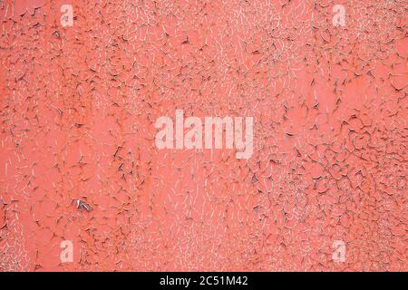 Old orange painted crumbling wall. Background of wall covered with crumbling old orange paint. Old cracked paint surface. Cracked wall with remnants Stock Photo