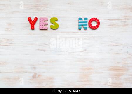 Words YES and NO of colorful letters on vintage wood background. Colored words YES and NO on wood background with copy space. Choosing right answer Stock Photo