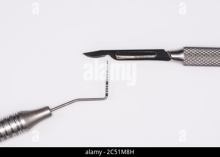 Horizontal color image with an overhead view of a professional dental tools on a white background. Periodontal probe and scalpel. Stock Photo
