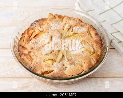 Freshly baked sweet and sour apple pie in a glass baking dish on a white wood table. Easy recipe for sweet homemade baking. Breakfast pastries. Stock Photo