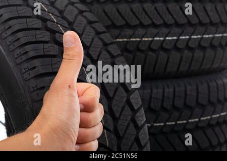 Close up picture of black new tyre and human hand showing thumbs up Stock Photo