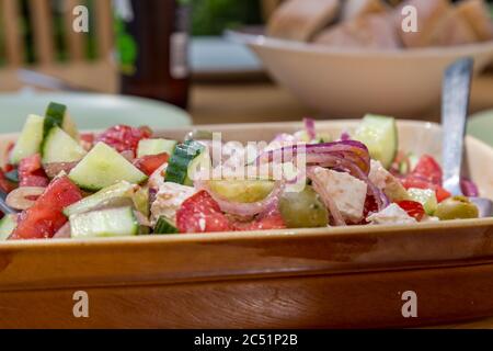 A bowl of salad on an outdoor table set for a summer lunch Stock Photo