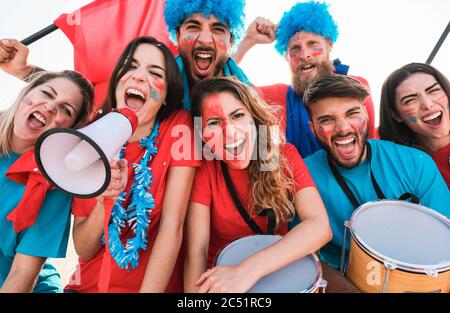 Crazy sport fans playing drums and screaming while supporting their team - Football supporters having fun inside stadium for soccer match - Event conc Stock Photo