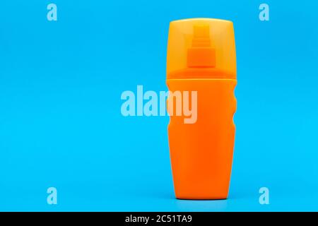 orange unlable bottle of sunscreen on a blue background with copy space. Stock Photo