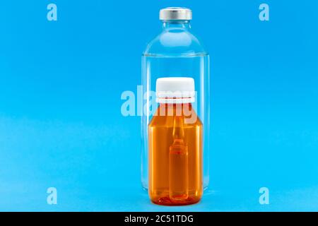 glass bottle with injection and orange plastic bottle with a yellow cap and an ampoule with a vaccine inside, medical concept on a blue background wit Stock Photo
